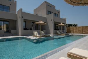 een huis met een zwembad met stoelen en parasols bij Casa Nostos in Agia Marina Nea Kydonias