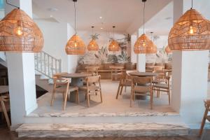 a restaurant with tables and chairs and pendant lights at Portomar Apartments - 4-Star Superior Hotel in Portocolom