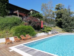 a swimming pool with chairs and a house at Là-Haut "Maison d'hôtes" in Antraigues