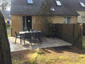 een patio met een tafel en stoelen en een hek bij Cottage T3 à 5 minutes à pied de la plage in Le Pouliguen