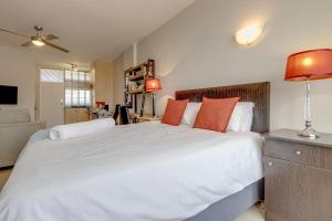 a bedroom with a large white bed with orange pillows at RAD STAYS - Illovo Mews 245 Oxford Road in Johannesburg