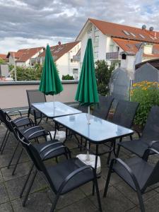 eine Gruppe von Tischen und Stühlen mit grünen Sonnenschirmen in der Unterkunft Ferienwohnung Michelle klimatisiert Alemannenstr 1 in 77977 Rust in Rust