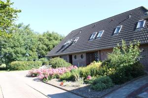 una casa con muchas flores delante de ella en Tetenshof für Pferdeliebhaber, en Westerhever