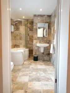 a bathroom with a tub and a sink and a toilet at Oak End Lodge in Sevenoaks