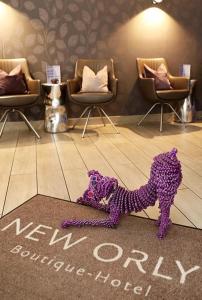 a purple dog on the floor in a room with chairs at Hotel New Orly in Munich