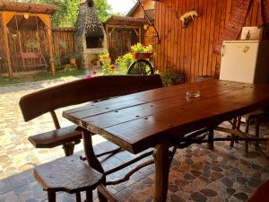 a wooden table and a bench and a refrigerator at Pensiunea Bujor de Munte in Cârțișoara