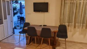 a dining room table with chairs and a television on the wall at Apartments Prižmić in Podstrana