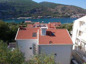 a white building with a red roof and a lake at Hygge Apartments in Mokošica