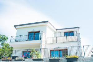 a white apartment building with balconies and plants at Encanto Agriturismo & Private SPA in Visogliano