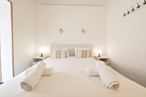 a white bedroom with a large white bed with towels on it at Stay U-nique Apartments Tapioles in Barcelona