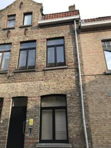 een bakstenen gebouw met ramen en een afvoer bij Maison HB in Ieper