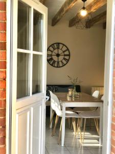 a dining room with a table and a clock on the wall at La Vove in Rouillon