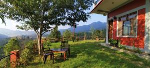 a house with a table and chairs in the grass at Oak Essence in Mukteshwar