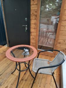 a small dog sitting in a table and chairs on a porch at Guest House Lory in Adler