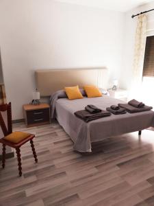 Un dormitorio con una cama con almohadas amarillas y una silla en Casa Martín, en Ávila