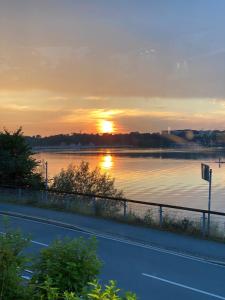 a sunset over a body of water with a road at Forsthaus am Möhnesee in Möhnesee