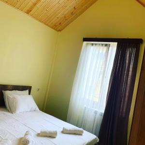 a bed with two towels on it next to a window at Royal Cottage in Ureki +12 photos