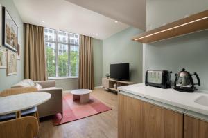 cocina y sala de estar con sofá y mesa en The Lincoln Suites, en Londres