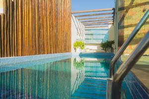 a swimming pool next to a building with a fence at Casa ampla com área de lazer na praia em Ilhéus in Ilhéus