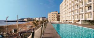 una piscina junto a una playa junto a un edificio en Hotel Cristina by Tigotan Las Palmas - Adults Only, en Las Palmas de Gran Canaria