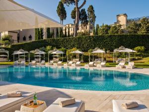 - une piscine avec des chaises longues blanches et des parasols dans l'établissement Villa Agrippina Gran Meliá – The Leading Hotels of the World, à Rome