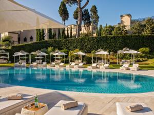 a swimming pool with white lounge chairs and umbrellas at Villa Agrippina Gran Meliá – The Leading Hotels of the World in Rome