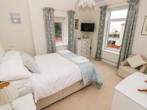 a bedroom with a bed and a tv and windows at The Headlands - Gower in The Mumbles