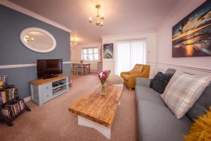 ein Wohnzimmer mit einem Sofa, einem TV und einem Tisch in der Unterkunft Beautiful Dawn - relax with stunning marina views in Pevensey