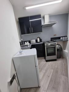 a kitchen with black cabinets and a white refrigerator at Bvapartments-Queensgate in Huddersfield