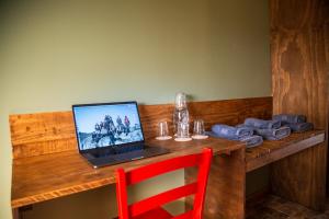 a laptop computer on a wooden table with a red chair at Hostal Esquina Patagónica in Coihaique