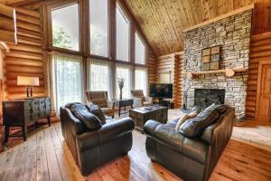 a living room with leather furniture and a stone fireplace at Grande Forêt by Tremblant Platinum in Mont-Tremblant