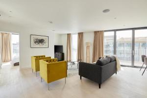 ein Wohnzimmer mit Sofas und gelben Stühlen in einem Gebäude in der Unterkunft Southwark by Q Apartments in London