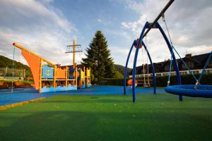 ein leerer Spielplatz mit Rutsche und Schaukeln in der Unterkunft Hotel Beskid BALNEO Medical Resort & SPA in Piwniczna-Zdrój