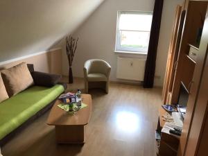 ein Wohnzimmer mit einem grünen Sofa und einem Tisch in der Unterkunft Ferienhaus Zur Heide - Obergeschoss in Radibor