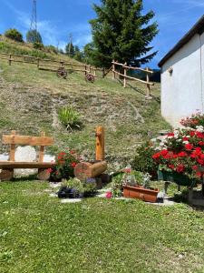un jardín con flores y un banco y una valla en Frazione Duc Apartments, en Sestriere
