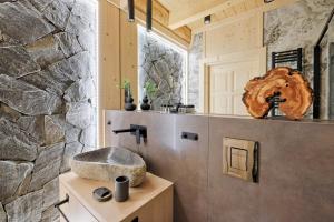 a bathroom with a sink and a stone wall at Osada Bachledzki Wierch Odkryj Zakopane in Zakopane +184 photos