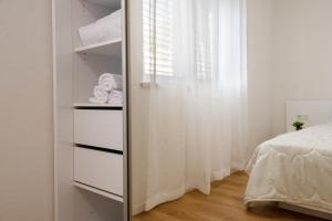 a bedroom with a closet with white curtains and a bed at Apartmani Vuletić in Neum