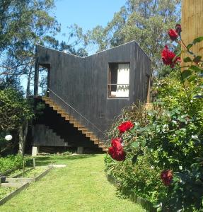 une maison noire avec des escaliers dans une cour ornée de roses dans l'établissement Posada IRSIS, à La Pedrera