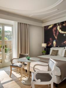 una camera con un grande letto e un tavolo con sedie di Villa Agrippina Gran Meliá – The Leading Hotels of the World a Roma