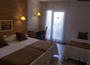 グアルダマル・デル・セグラにあるHotel Guardamarのベッド2台、デスク、窓が備わるホテルルームです。