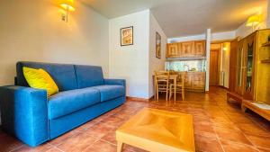 a living room with a blue couch and a kitchen at Appartamento Smith Ruché - Affitti Brevi Italia in Bardonecchia