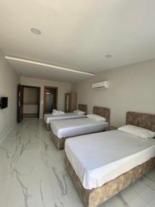 two beds in a hotel room with marble floors at Prestij Suit in Alanya