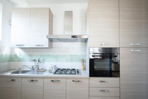 a kitchen with white cabinets and a stove and a sink at Blue Fish Home in Giardini Naxos