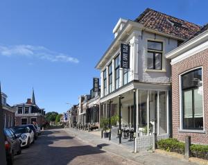una calle con edificios y coches estacionados en la calle en Zee van Tijd Holwerd en Holwerd