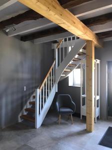 a white staircase in a room with a chair at Fachwerk-Maisonette-Wohnung „Am Giebel“ in Rieste