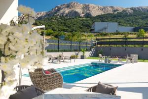 a resort pool with chairs and a mountain in the background at Villa Aurora in Baška
