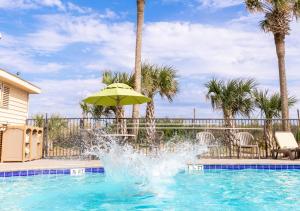 a pool with an umbrella and a fountain at Surfside Beach Oceanfront Hotel in Myrtle Beach