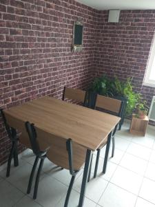 le gîte de manu 3 personnes في Lambres: طاولة وكراسي خشبية أمام جدار من الطوب
