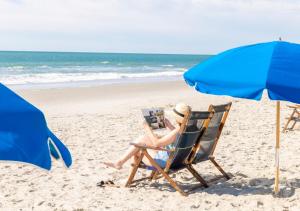 a woman sitting in a chair on the beach at Surfside Beach Oceanfront Hotel in Myrtle Beach