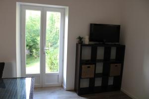 sala de estar con TV y ventana en Petit maison du Vallon en Marcillac-Vallon